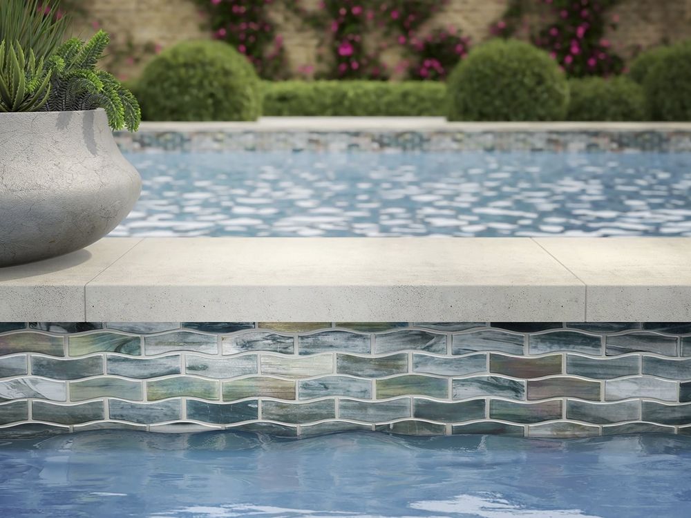 Stone coping and iridescent tile on a finished pool edge