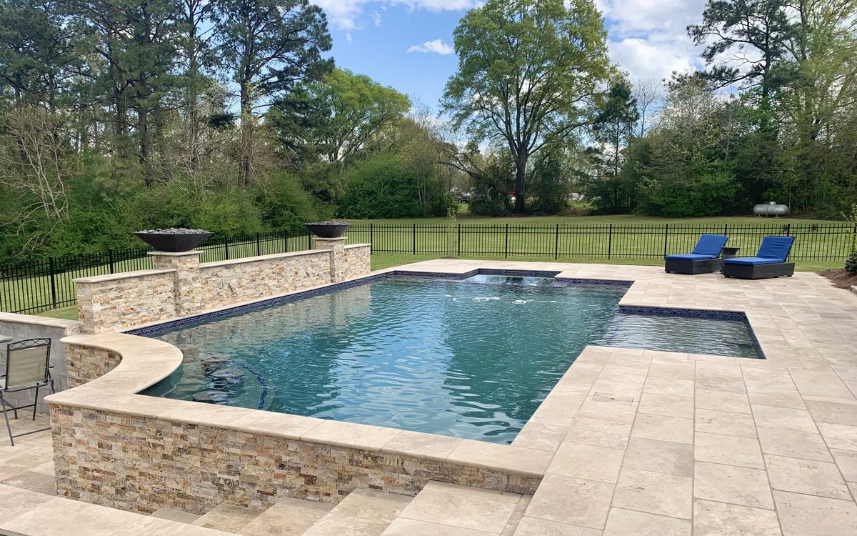 Geometric pool with stacked-stone wall and travertine deck