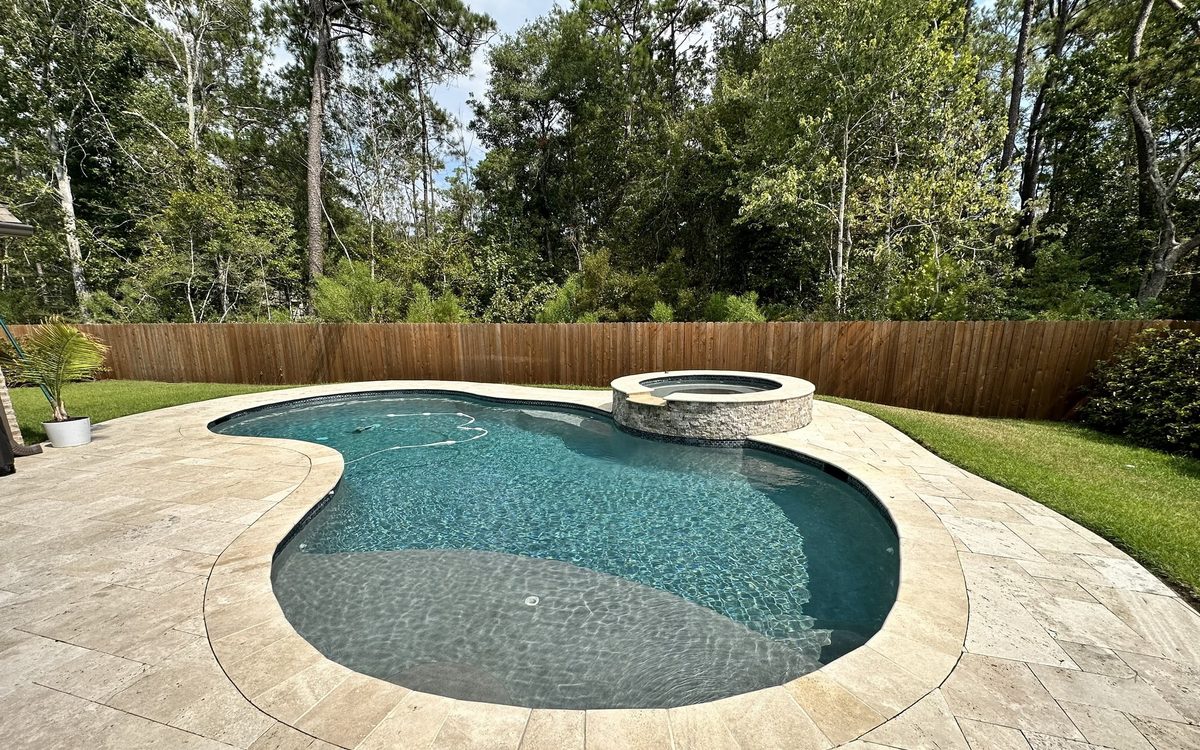 Free-form gunite pool with raised stacked-stone spa and stone deck