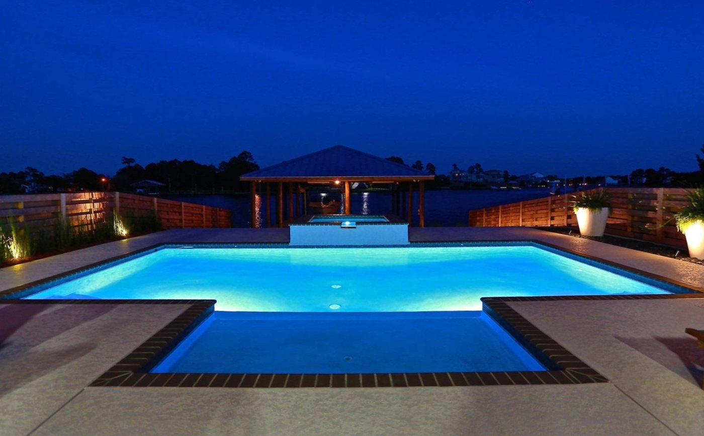 Night-lit geometric pool with raised spa and pavilion